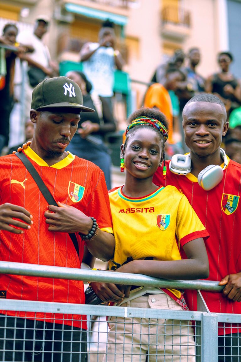Enthusiastic soccer fans wearing team jerseys at an outdoor event, enjoying the game and showing support.